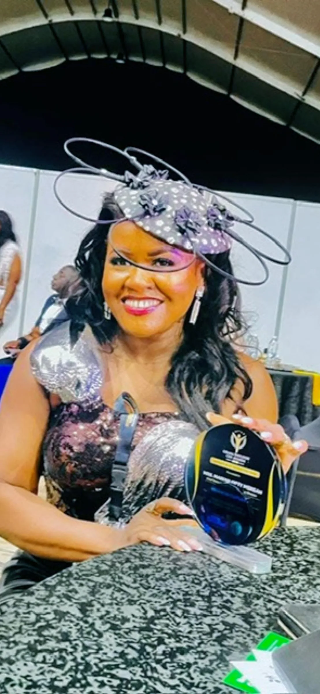 Mrs. Marian Gifty Mensah-Dossah holding a Triumph Fashion Icon trophy, a gold-and-black trophy with a star on top.