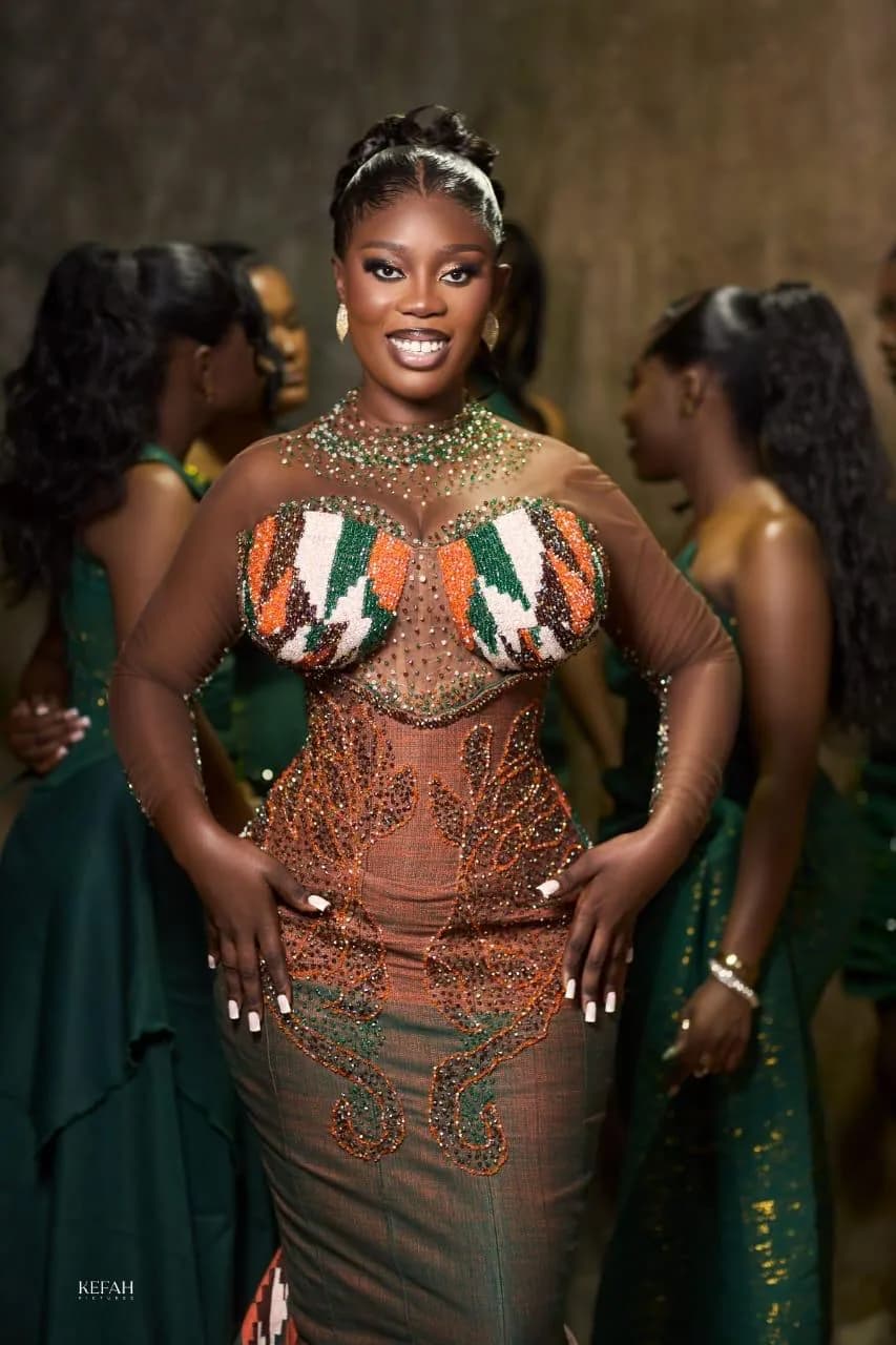 Client in a hand-beaded Magmens Couture corseted gown with a Kente-panel bust, crystal-embroidered overlay and fitted skirt, photographed at a wedding reception.